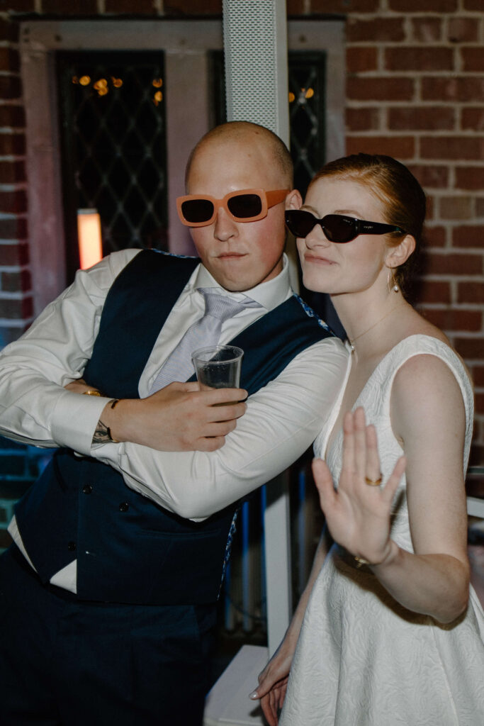 Bride and groom strike a silly pose with sunglasses on their faces