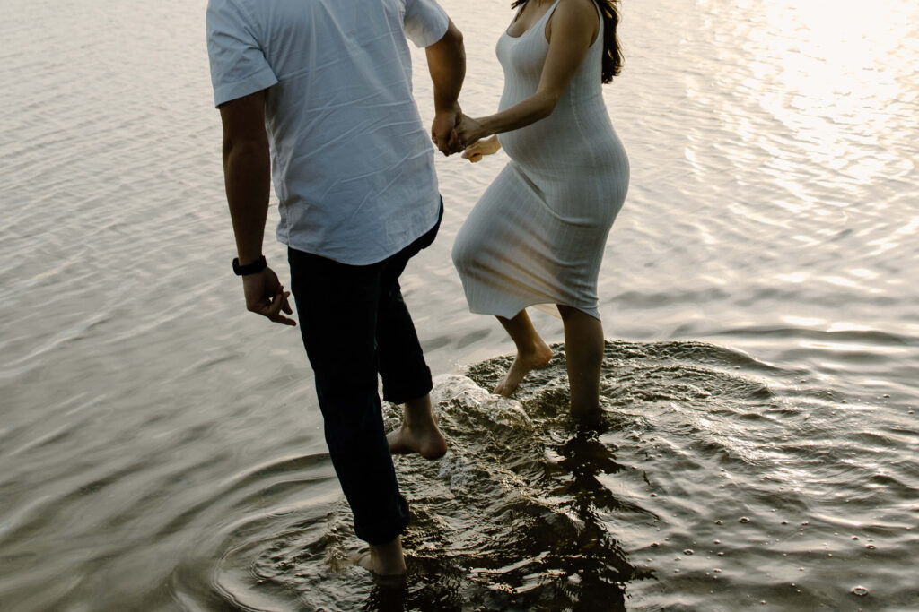 Man and woman holds as they walk through the shallow water of Bde Mka Ska.