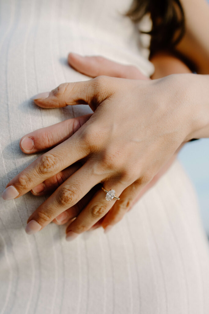 Man and woman put their hand on her expecting belly.